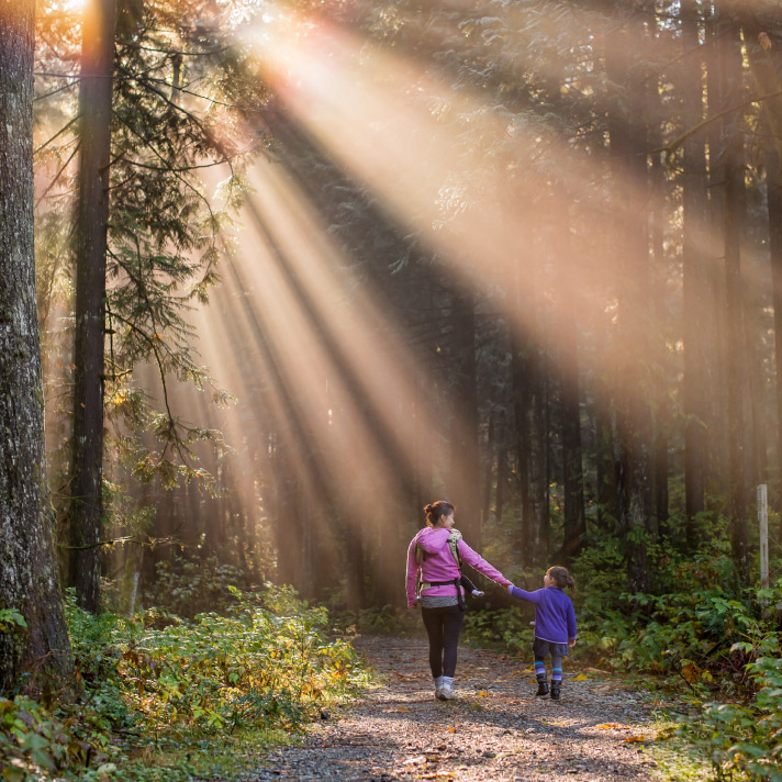 Woman and her daughter walking in a wooded area